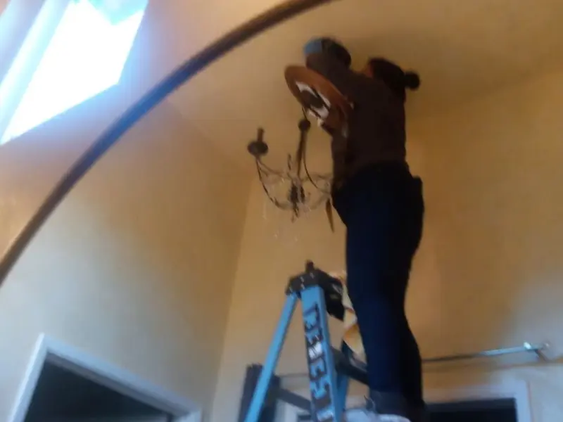 Electrician installing a chandelier in a Taylors residence